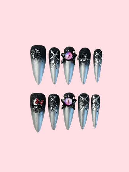 BLACK AND SILVER GOTHIC HALLOWEEN PRESS-ON NAILS WITH 3D SPIDER, SKULL, AND DRAGON EYE CHARMS.
