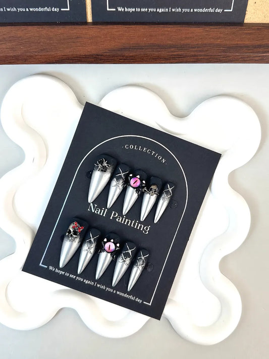 GOTHIC STILETTO NAILS WITH BLACK GLITTER, SILVER TIPS, AND HALLOWEEN CHARMS.